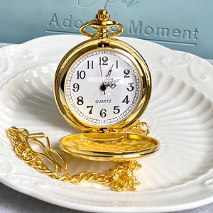 Vintage golden Alice themed flip pocket watch with chain on an elegant gift box background
