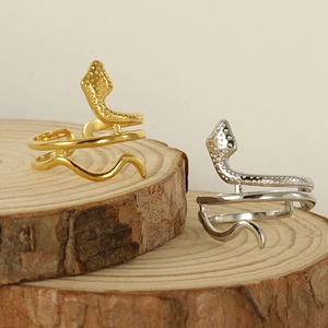 Adjustable snake-shaped rings in gold and silver steel finish on wooden display