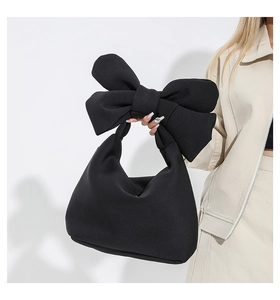 Detail of the oversized bow handle on a black quilted puffy shoulder bag for women