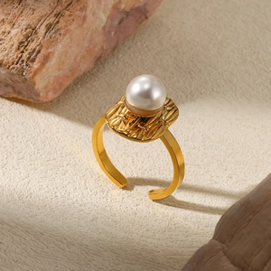 Macro detail of gold-plated open ring with irregular texture and white pearl inlay