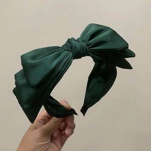 Detail of the multi-layer dark green fabric bow headband with a voluminous retro design