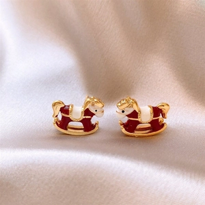 Vue macro de boucles d'oreilles cheval à bascule en émail rouge sur fond de soie champagne