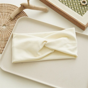Detail of a creamy white knitted twist headband on a minimalist beige tray