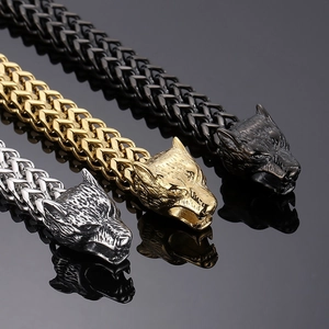 Detailed view of woven metal chains with wolf head pendants in silver, gold, and black