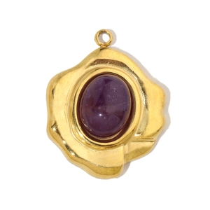 Detail of vintage gold-plated drop pendant with a large purple gemstone and teardrop design