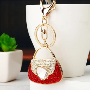 Detail of a handbag-shaped keychain featuring red and white rhinestones and a heart crystal