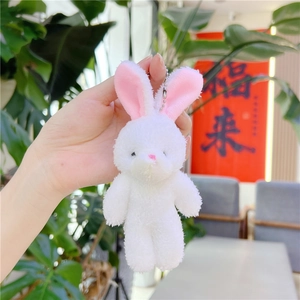 Gros plan sur un pendentif lapin en peluche blanche douce avec oreilles roses et chaîne