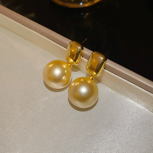Vue macro de boucles d'oreilles perles champagne plaquées or 18K dans un écrin