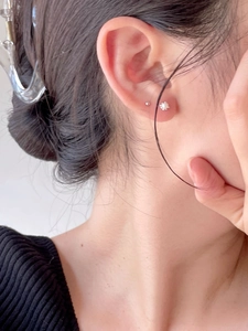 Close-up of minimalist S925 silver pearl stud and small metal ball on model ear