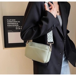 Close-up of light green crossbody bag with lychee texture and wave pattern wide strap