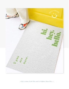 Detail of white PVC door mat with green text you are here on bright yellow background