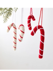 Détail macro de cannes de Noël en feutre de laine rouge et blanc sur une branche de sapin
