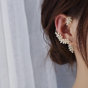 Macro detail of leaf-shaped gold ear cuff earrings with sparkling zircon gemstones
