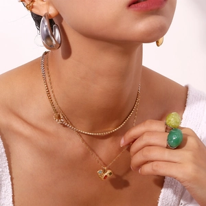 Close-up of 18K gold plated crescent hoop earrings with matching emerald stone ring