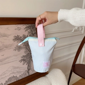 Detail of light blue canvas stationery pouch with pink handle and durable top zipper