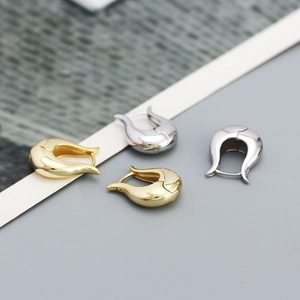 Detailed view of curved horseshoe metal earrings in polished gold and silver finishes
