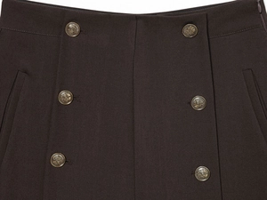 Dettaglio macro dei pantaloncini marroni con sei bottoni vintage dorati goffrati