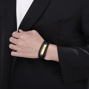 Detail of multilayer black braided leather bracelet with a gold rectangular metal clasp
