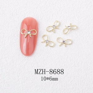 Macro detail of 10x6mm gold alloy bow nail art charm with a central sparkling rhinestone