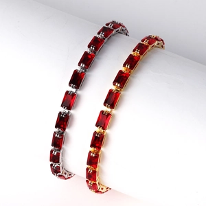 Macro view of gold and silver bracelets with rectangular red zircon stones on a white stand
