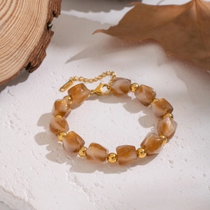Close-up of amber resin beads with gold flakes and metallic accents on wood background