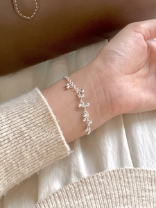 Close-up of 925 sterling silver beaded bracelet with mini charms on female wrist