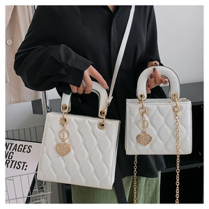 Detail showing two sizes of white quilted patent leather bags with gold heart charms