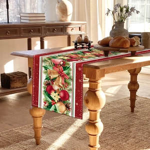 Detail of Christmas table runner with golden bells, holly berries and pine branches