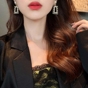 Detailed view of vintage gold-framed black trapezoid earrings with elegant white pearl