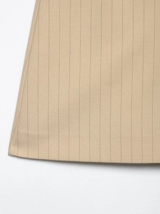 Nahaufnahme von beige Stoff mit dunklen vertikalen Streifen eines eleganten Zweiteilers