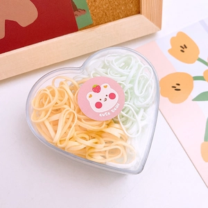 Close-up of heart-shaped storage box filled with yellow and green elastic hair bands