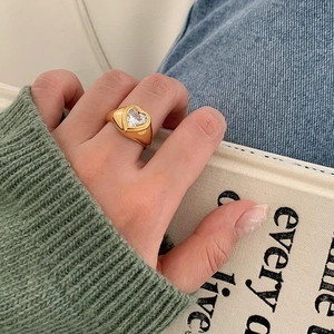 Close-up of vintage gold heart ring with large clear zircon worn on a index finger