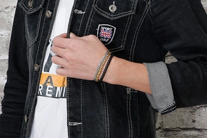 Close-up of a three-piece men's leather and chain bracelet set in black, gold, and silver