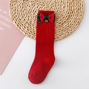 Close-up of red knit socks with a festive red-green bow and small golden bell