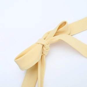Macro view of cream yellow fabric bow tie detail with refined texture and stitching