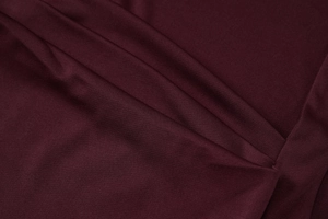 Détail macro du tissu bordeaux montrant la maille fine et le drapé élégant