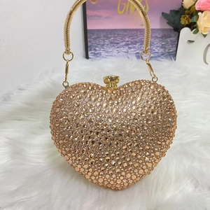 Detailed view of the sparkling champagne rhinestone heart clutch bag with a golden metal ring handle