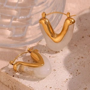 Detail of 18K gold-plated triangular earrings with white resin inlay on a stone slab