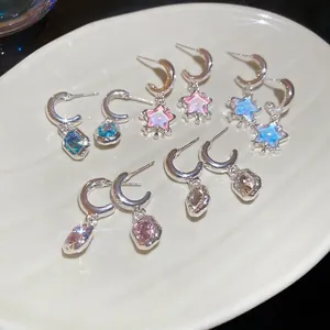 Star resin pendant C-shape hoop earrings with crystal drops on a ceramic tray