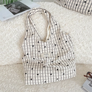 Detailed view of cream canvas tote bag with black plaid and heart print on a plush rug