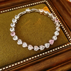 Détail macro du bracelet en zircone avec cœurs roses sur plateau en velours vert