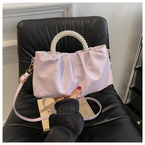 Detailed view of lavender pleated cloud bag with faux pearl handle on a black seat