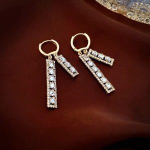 Detailed view of long gold drop earrings with sparkling rectangular cubic zirconia gems