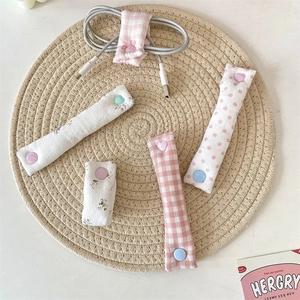 Detailed view of floral and plaid fabric cable organizers with colorful heart-shaped snaps