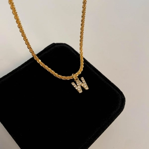 Gros plan détaillé du pendentif lettre W serti de zircones sur une chaîne torsadée en or