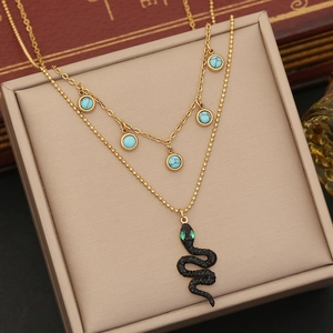Double-layered gold necklace with turquoise beads and black snake pendant on jewelry box