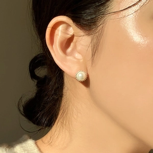Close-up of minimalist white pearl stud earrings with metallic beaded edges on model