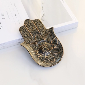 Detail of Hamsa hand ceramic jewelry tray with gold evil eye pattern on black glaze