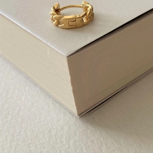Detailed view of a gold chain link ring resting elegantly on an open book corner