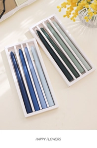 Detail of colorful gradient taper candles in blue and green sets within gift boxes